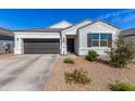 Inviting single-story home with xeriscaping, black front door, and shutters, enhanced by manicured landscaping at 5180 E Diatomite Dr, San Tan Valley, AZ 85143