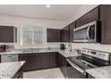 Modern kitchen featuring stainless steel appliances, sleek dark brown cabinetry and granite countertops at 5180 E Diatomite Dr, San Tan Valley, AZ 85143