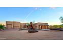 Exterior front view of a custom home showcasing desert landscaping, a sculpture, and a circular driveway at 13935 E Smokehouse Trl, Scottsdale, AZ 85262