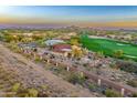 Expansive aerial view of a desert community with golf course, mountain views and tile roofs at sunset at 2430 S Geronimo Head Trl, Gold Canyon, AZ 85118