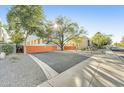 Street view showcasing the building behind a secure, bright orange gate with mature trees at 7047 E Earll Dr # 1002, Scottsdale, AZ 85251