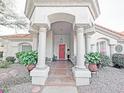 Inviting front porch featuring white columns, a red door, decorative plants, and charming accents at 14236 N 28Th St, Phoenix, AZ 85032
