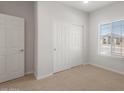 Bright bedroom with carpet, a large window, and closet with mirrored doors, offering ample storage space at 17845 W Getty Dr, Goodyear, AZ 85338