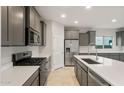 Modern kitchen featuring stainless steel appliances, gray cabinets, a large island with countertop, and stylish travertine tile at 2681 N Riverside Dr, Florence, AZ 85132