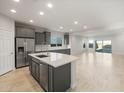 Spacious open-plan kitchen with stainless steel appliances, grey cabinets, large island, and travertine-style tile floors at 2681 N Riverside Dr, Florence, AZ 85132