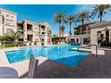 Resort style swimming pool with lounge chairs and umbrellas, surrounded by palm trees and condo buildings at 5303 N 7Th St # 242, Phoenix, AZ 85014