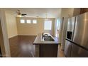 A modern kitchen with stainless steel refrigerator, island sink and view of the adjacent living space at 10039 W Kingman St, Tolleson, AZ 85353