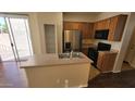 The kitchen features stainless steel appliances, a central island, and ample cabinet space, all illuminated by natural light at 10039 W Kingman St, Tolleson, AZ 85353