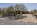 Desert home with stone accents, three-car garage, and desert landscaping in front yard at 15135 E Monument Rd, Scottsdale, AZ 85262