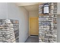 Close-up of a home's stone-accented entrance featuring a yellow door and house number at 24220 W Ripple Rd, Buckeye, AZ 85326