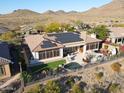 Aerial view of a home with solar panels, pool, lush landscaping, and mountain views at 3109 W Summit Walk Ct, Anthem, AZ 85086