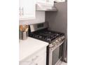 Close-up of the kitchen features stainless steel gas range, white cabinets and modern finishes at 4112 N 11Th St, Phoenix, AZ 85014