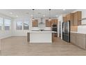 Bright kitchen features wood floors, a large center island, stainless steel appliances, and modern lighting at 7987 W Griswold Rd, Peoria, AZ 85345