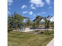 Community playground features picnic benches and seating areas with shade structures and mature trees at 21141 E Canary Way, Queen Creek, AZ 85142