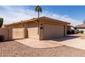 Exterior view of the home, featuring an attached garage, gated side yard, and desert-style landscaping at 25620 S Cloverland Dr, Sun Lakes, AZ 85248