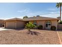 Single-story home with desert landscaping, showcasing arched windows and a classic design at 25620 S Cloverland Dr, Sun Lakes, AZ 85248