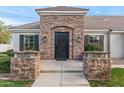 Elegant stone facade frames a custom metal front door, accented by manicured shrubs and stone accents at 2838 E Vaughn Ct, Gilbert, AZ 85234