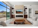 Bright living room features a stacked stone fireplace, built-in shelving, and expansive windows showcasing scenic views at 4201 E Claremont Ave, Paradise Valley, AZ 85253