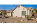 Side view of charming single-story home with low maintenance desert landscaping, neutral paint, and an attached two-car garage at 5440 W Voltaire Dr, Glendale, AZ 85304