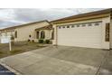 Home exterior with a wide driveway leading to an attached garage with windows, stucco finish, and desert landscaping at 10960 E Monte Ave # 283, Mesa, AZ 85209