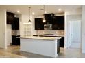 This kitchen features granite countertops, dark cabinets, stainless appliances and an island with a sink and pendant lighting at 14132 W Valentine St, Surprise, AZ 85379