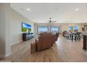 Spacious living room with hardwood floors, large windows, a ceiling fan, and comfortable seating at 18601 W Thunderhill Pl, Goodyear, AZ 85338