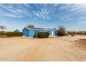 Blue single story house with solar panels and a circular drive set in a rural neighborhood at 30446 W Portland St, Buckeye, AZ 85396