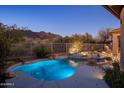 Resort-style pool with stone accents, lush landscaping, and views of the surrounding mountains at 6576 E Whispering Mesquite Trl, Scottsdale, AZ 85266