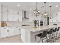 Bright kitchen featuring white cabinets, stainless steel appliances, and a large quartz countertop island with pendant lighting at 10713 E Tesla Ave, Mesa, AZ 85212