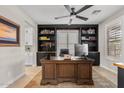 Office space showcasing a grand wooden desk, custom built-in shelving, and a modern ceiling fan at 10713 E Tesla Ave, Mesa, AZ 85212