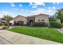 Beautiful home exterior with a lush green lawn, desert landscaping, and a stone-accented entryway at 11141 E North Ln, Scottsdale, AZ 85259