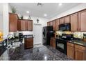 Well-lit kitchen featuring granite counters, and wooden cabinetry with black appliances at 1475 N Agave St, Casa Grande, AZ 85122