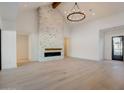 Bright and airy living room with whitewashed brick fireplace, beamed ceiling, hardwood floor, and modern chandelier at 11841 N 65Th Pl, Scottsdale, AZ 85254