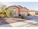 View of a well-maintained tan home featuring a two-car garage and desert landscaping at 18842 N Lariat Rd, Maricopa, AZ 85138