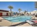 Sparkling community pool with lounge chairs, a covered picnic area, and lush palm trees at 2228 W Harmont Dr, Phoenix, AZ 85021