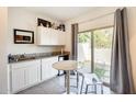 A kitchenette with granite countertops, white cabinets, mini fridge and glass doors to backyard at 2228 W Harmont Dr, Phoenix, AZ 85021