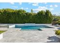 Beautiful outdoor pool with tiled patio, green plants, and manicured hedges at 3675 E Strawberry Dr, Gilbert, AZ 85298