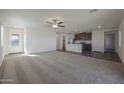 Spacious living room with plush carpeting and a ceiling fan with connected kitchen at 666 W Pintail Dr, Casa Grande, AZ 85122