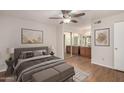 Comfortable main bedroom featuring a ceiling fan, wood-look floors, and ensuite bath with double sink vanity at 9355 N 91St St # 113, Scottsdale, AZ 85258