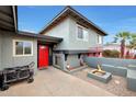 Gray home with a red front door and a small outdoor living space with a fire pit at 11652 N 49Th Dr, Glendale, AZ 85304