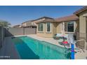 Private pool surrounded by patio, bordered by block fence, and umbrella providing shade at 18187 W Via Montoya Dr, Surprise, AZ 85387