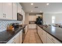 Bright kitchen features white cabinets, dark countertops, stainless steel appliances, and a large island at 18187 W Via Montoya Dr, Surprise, AZ 85387
