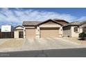 Home exterior featuring a spacious three car garage and a well-maintained desert landscaped yard at 18542 W Luke Ave, Litchfield Park, AZ 85340