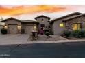 Home exterior showcasing a three-car garage, stone accents, desert landscaping, and a charming front entrance at 27708 N 110Th Pl, Scottsdale, AZ 85262
