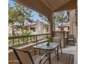 Relaxing balcony with a glass-top table and chairs, offering views of lush landscaping and neighboring buildings at 9710 N 94Th Pl # 216, Scottsdale, AZ 85258