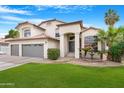 Beautiful two-story home with a tile roof, lush green lawn, palm trees, and a charming water fountain at 1225 E Sea Gull Dr, Gilbert, AZ 85234