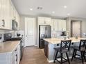 Open kitchen features white cabinets, an island with bar seating, stainless appliances, and subway tile at 18902 W Clinton St, Surprise, AZ 85388