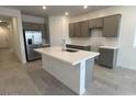 Modern kitchen features a central island, stainless steel refrigerator, and sleek gray cabinetry at 25170 W Wayland Dr, Buckeye, AZ 85326