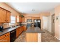 Functional kitchen features wood cabinetry, a center island, black appliances and tile flooring at 33425 N Roadrunner Ln, San Tan Valley, AZ 85144