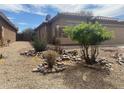 Tan single-story home featuring a tile roof, a two-car garage, and a gravel yard with shrubbery at 43857 W Bedford Dr, Maricopa, AZ 85138